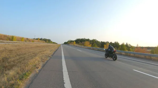 秋の高速道路で現代のスポーツバイクに乗るバイカーに従ってください オートバイ愛好家は田舎道でバイクレースをしている 旅行中に自転車を運転する男 自由と冒険の概念 空中射撃 — ストック写真