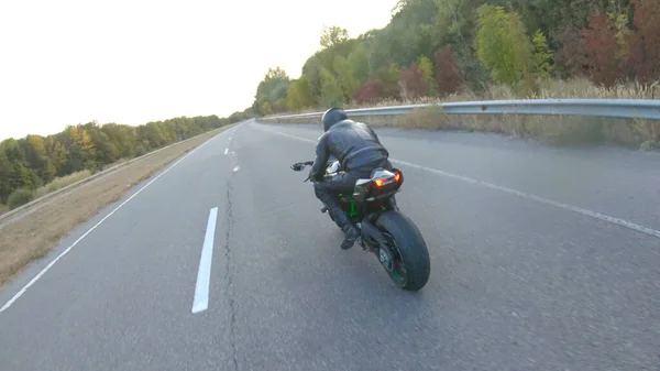 Otobanda motosiklet süren motosikletli bir motorcunun kamera görüntüsü. Motosikletli gün batımında kır yolunda motosikletiyle yarışıyor. Yolculuk sırasında bisiklete binen adam. Özgürlük ve macera kavramı.