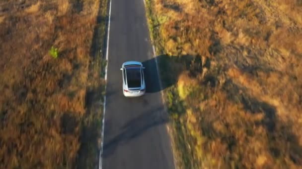 Aerial shot of electrical car driving on country road with beautiful nature environment around. New SUV vehicle moving fast at route. Ecology clean auto riding on electric charge along motorway — Stock Video