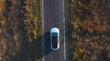 Yaz akşamları kır yolunda uçan elektrikli arabanın görüntüsü. Yeni bir SUV aracı otobanda hızla ilerliyor. Çevre dostu araba otoyol boyunca elektrik yükü ile gidiyor. Üst Görünüm Kapat.
