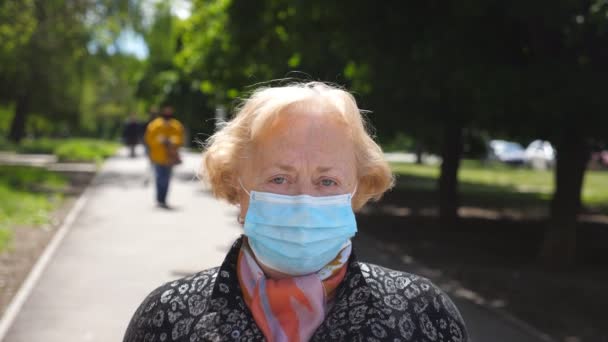 Retrato de mulher idosa com máscara facial médica stand na rua da cidade. A avó feliz tira a máscara protetora do vírus COVID-19 e sorri. Conceito de saúde e segurança da pandemia de coronavírus — Vídeo de Stock