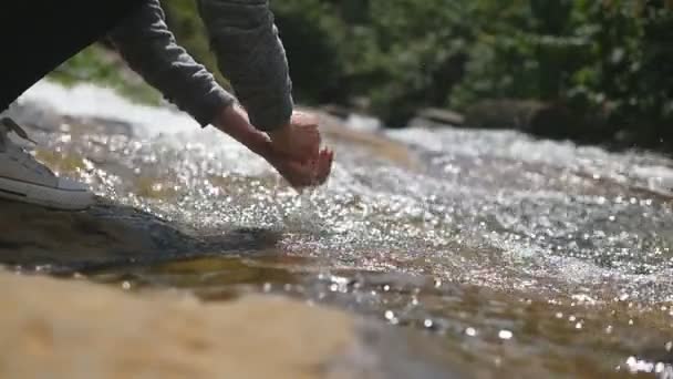 Junge Wanderin wäscht ihre Hände im klaren Wasser des Gebirgsflusses. Eine unkenntliche Frau erfrischt ihre Arme mit kaltem Wasser im Waldsee. Konzept von Abenteuer oder Reise. Zeitlupe — Stockvideo