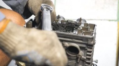 Tanımlanamayan tamirci, araç kullanarak otomobil motorunu tamir ediyor. Otomobil ustası araçtan motoru tamir ediyor. Otomatik serviste çalışan bir adam. Tamirci garajda ya da atölyede çalışıyor. Yavaş çekim. Yakın çekim.