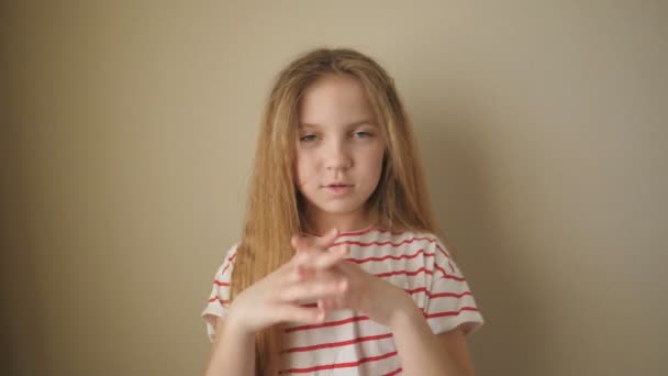 Πορτρέτο του μικρού ξανθού κοριτσιού κοιτάζοντας στην κάμερα και παλαμάκια τα χέρια της με ειρωνεία σε εσωτερικούς χώρους. Ένα μικρό θηλυκό παιδί χειροκροτεί σαρκαστικά στο φόντο του μπεζ τοίχου. Κλείσιμο Αργή κίνηση — Αρχείο Βίντεο