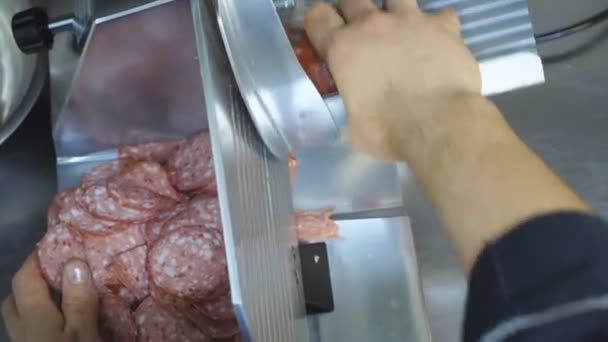 Manlig hand kock med hjälp av skärmaskin för salami på köket restaurang. Arm av kock hacka korv på elektrisk mat skivare i köket. Process för att förbereda ingredienser för matlagning maträtt. Ovanifrån — Stockvideo