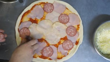 POV erkek kolu, hamur işine salam dilimlerini tahta yüzeyde metal formda koyuyor. Genç aşçı mutfak restoranında pepperonili pizza hazırlıyor. Yemek pişirme kavramı. Üst Görünüm Yavaş Çekim