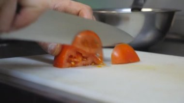Aşçının erkek elleri mutfak restoranında plastik kesme tahtasıyla taze kırmızı domates dilimliyor. Sağlıklı sebze salatası hazırlama süreci. Yemek pişirme kavramı. Yavaşça kapat.