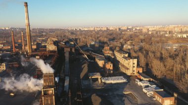 Bitki borularından yayılan hava manzaralı duman sütunu. İnsansız hava aracı sanayi bölgesinin üzerinde uçuyor. Havaya zehirli buhar saçıyor. Arka planda büyük şehir olan manzaralı bir yer. Doğa kirliliği sorunu. Üst görünüm.