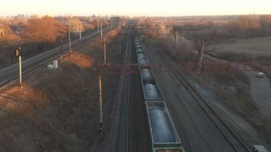 Demiryolu boyunca hareket eden ve endüstriyel malları taşıyan bir trenin havadan çekimi. Taşıma vagonları kırsaldan geçerken endüstriyel lokomotifin üzerinde uçan insansız hava aracı. Kargo taşımacılığı veya teslimat kavramı