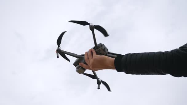 Vista baixa para quadricóptero a sair da mão masculina. Operador de drones tacking imagens aéreas ou filmagem de vídeo de ambiente cênico. Conceito de tecnologia moderna. Movimento lento — Vídeo de Stock