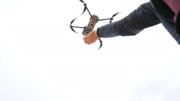 Low view to quadcopter landing on male pilot hand. Drone operator tacking aerial pictures or filming video of scenic environment. Modern technology concept. Slow motion — Stock Video