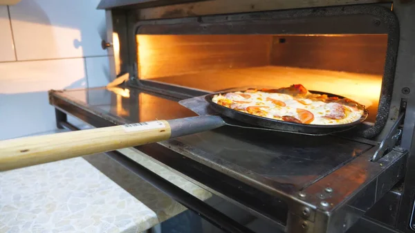 삽으로 오븐에서 맛있는 피자를 식탁에 놓는다 요리사가 식당에서 맛있는 요리를 — 스톡 사진