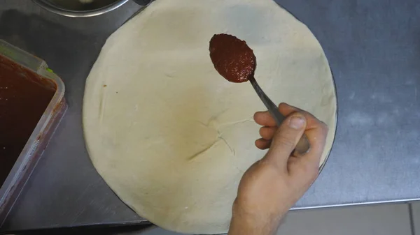 Männliche Hand Des Kochs Verteilt Tomatensauce Auf Pizzateig Mit Einem — Stockfoto