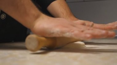 Lokantadaki mutfak masasında merdane kullanarak hamur işi açarken kollarını kapat. Aşçının erkek elleri mutfakta ahşap bir yüzeye hamur döküyor. Pizza yapma süreci. Yavaş çekim