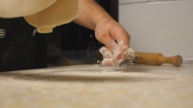 Lokantada ahşap bir yüzey üzerinde hamur işi oluşturan erkek kolları. Mutfak masasında pizza için un hamuru şekillendiren şefin elleri. Yemek hazırlama kavramı. Yavaşça kapat.