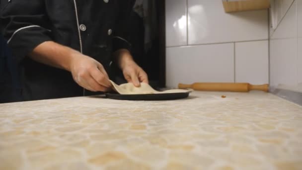 Tangan laki-laki dari memasak menempatkan adonan dalam bentuk logam untuk pizza pada permukaan kayu pada masakan. Lengan muda koki menyiapkan kue untuk dipanggang di atas meja di restoran. Konsep makanan memasak. Tutup. — Stok Video