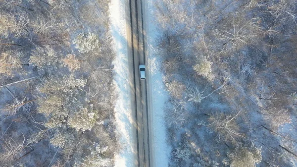 越野车冬季在森林里美丽的乡间小径上行驶 空中拍摄白色的汽车骑在雪地覆盖着结冰的道路上 从汽车上飞过 穿过风景秀丽的风景 顶部视图 — 图库照片