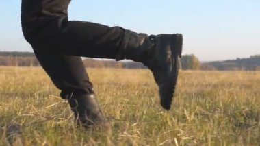Siyah çizmeli askerin ayakları tarlada koşuyor ve kuru çimlere basıyor. Erkek sporcu dışarıda antrenman ve egzersiz yapıyor. Arka planda güzel bir doğa. Askeri bir kavram. Yavaş çekim. Yakın çekim.