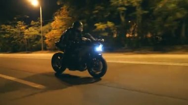 Miğferli genç adam şehir caddesinde modern siyah spor motosikletle hızlı gidiyor. Motosikletli, boş yolda motosikletiyle yarışıyor. Bisikletli adam. Özgürlük ve hobi kavramı. Kapat.