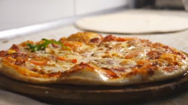 Mutfak restoranında biberli pizzayı roka eşliğinde bitiren eldivenli aşçının erkek eli. Mutfakta ahşap bir tahtanın üzerinde nefis pişmiş yemek. Yemek hazırlama kavramı. Yavaş çekim