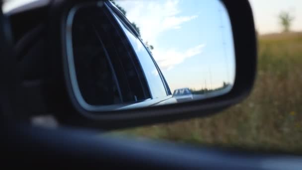 Vue sur la circulation routière et beau ciel réfléchissant dans le miroir latéral de la voiture en mouvement. Automobile conduite le long de la route de campagne le jour d'été. Concept vacances ou voyage. Gros plan Mouvement lent — Video