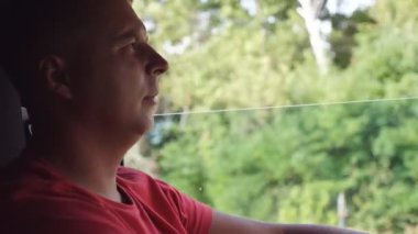 Kamyon şoförünün profili kırsaldan geçiyor. Taşra yolunda araba kullanan yetişkin bir kamyoncu. Hedefe doğru at süren adam. Lojistik ve ulaşım konsepti. Yavaşça kapat.