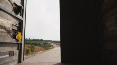 Erkek sürücü kırsal bölgedeki kamyonun arka kapısını kapatıyor. Lorry Country Road 'a park etmiş. Araba malları teslim etmeye hazır. Minibüsün içinden bak. Lojistik konsept. Yavaşça kapat.