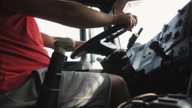 Kamyon şoförünün erkek kolları kırsalda kamyon sürerken büyük bir direksiyon tutuyor. Kamyon şoförü varış noktasına gidiyor. Lojistik ve ulaşım konsepti. Düşük görünüm Yavaş çekim