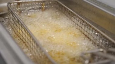 Çıtır patatesler mutfakta kızgın yağda kızartılıyor. Lezzetli patates kızartmaları mutfakta fritöze dönüşüyor. Fast food yapma süreci. Yemek hazırlama kavramı. Üst Görünüm Yavaş Çekim