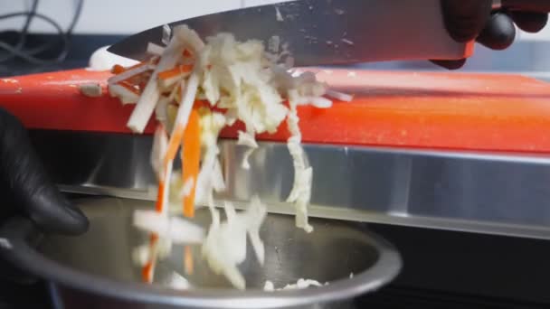 厨师用刀叉把配料从切菜板上扔到碗里.大白菜、鸡蛋和螃蟹条混合在一起做沙拉的男性厨师手。食品准备的概念。靠近点 — 图库视频影像