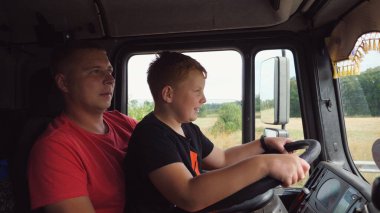 Kamyon şoförü, küçük kızıl saçlı oğluna boş bir kır yolunda araba kullanmayı öğretiyor. Konsantre küçük çocuk ellerini direksiyonda tutuyor babasının kucağında oturuyor ve kamyon sürmeyi öğreniyor..