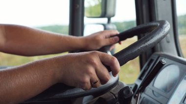 Kamyon şoförünün erkek elleri kırsal alanda kamyon kullanırken büyük bir direksiyon tutar. Kamyon şoförü varış noktasına gidiyor. Lojistik ve ulaşım kavramı. Kapat..