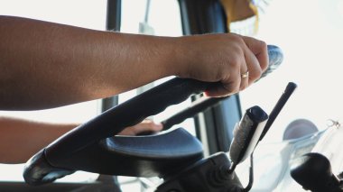 Kamyon şoförünün erkek kolları güneşli bir günde kamyon kullanırken büyük bir direksiyon tutar. Kamyon şoförü varış noktasına gidiyor. Lojistik ve ulaşım kavramı. Yavaşla..