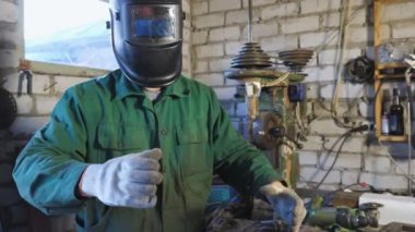 Müziğin ritmine göre robot hareketleri yapan mutlu bir tamirci. Garajdaki robot gibi komik dans eden üniformalı bir erkek kaynakçı. Neşeli adam koruyucu maskeyi açar ve güler ve kameraya bakar. Dolly vurdu.