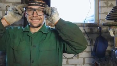 Genç tamirci koruyucu gözlüğünü çıkarıyor ve suratını ekşitiyor. Üniformalı kaynakçının portresi komik suratlar yapıp garajda aylaklık ediyor. Atölyede çalışan sakallı bir tamirci.