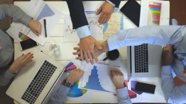 Başarı kutlayan dört iş adamının üst görüntüsü. Bir grup işveren neşe içinde tek tek kollarını birleştirdi. Modern ofiste çalışan yaratıcı ekip. Başarı konsepti