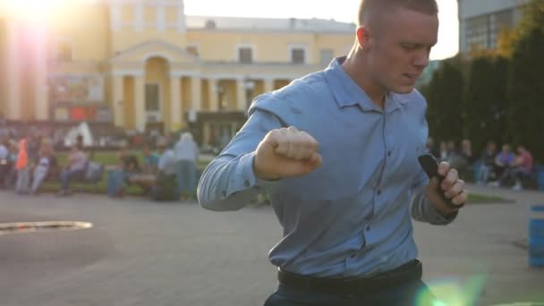 Jeune homme d'affaires célébrant les réalisations debout à l'environnement de la ville. Homme réussi recevant de bonnes nouvelles sur smartphone et ayant des émotions positives. Un gars qui se réjouit du succès. Ralenti Fermer — Video