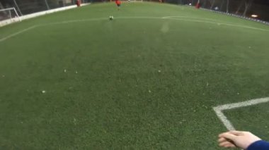 Futbolcunun akşam saatlerinde futbol sahasında antrenman yapmasına bakış açısı. Adam topa sürüp rakibine vurmaya çalışıyor. Adam topu arkadaşına atıyor. Boş zaman konsepti. POV