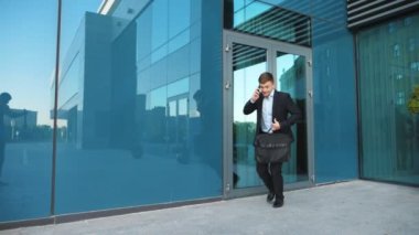 Evrak çantalı genç bir işadamı telefonla konuşuyor ve koşmaya başlıyor. Kendine güvenen adam buluşmaya geç kaldı. Takım elbiseli bir ofis çalışanı modern binanın yanında çalışır. Randevu için acele eden yakışıklı adam. Yavaş çekim