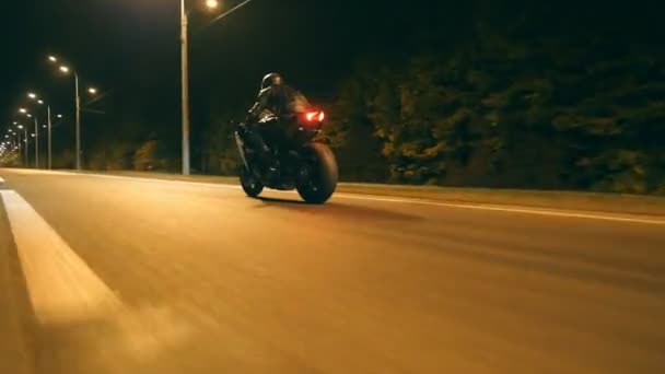 Uomo in sella veloce su moto sportive moderne a Nighty City Street. Motociclista corse la sua moto su strada vuota. Un tizio che guida la bici al tramonto. Concetto di libertà e avventura. Angolo di vista basso Primo piano — Video Stock
