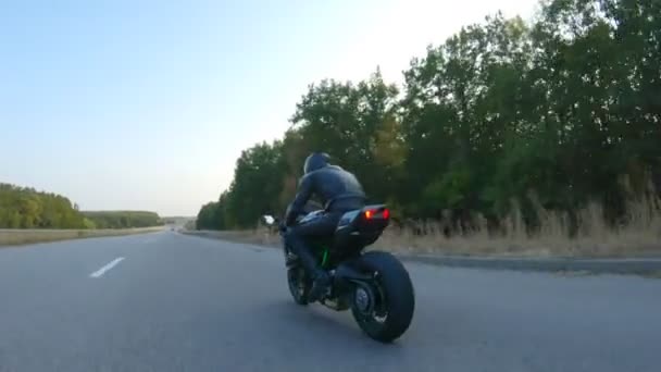 高速道路でスポーツバイクに乗ってヘルメットにオートバイに従ってください。男は秋の田舎道でバイクレースをしている。旅行中にバイクを運転する男。自由と冒険の概念。空中射撃 — ストック動画