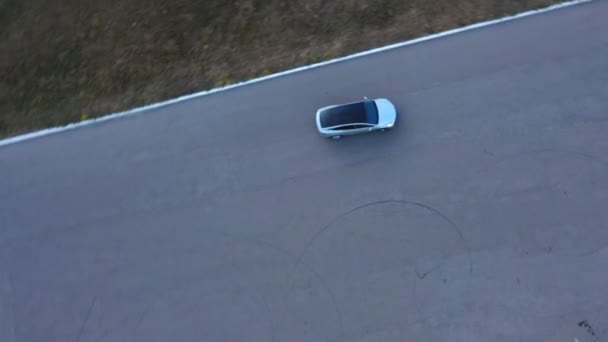 Toma aérea de coche eléctrico conduciendo en círculo. Nuevo vehículo todoterreno girando en el aparcamiento. Ecología automóvil amistoso que se mueve en la carretera de asfalto. Vista superior — Vídeo de stock