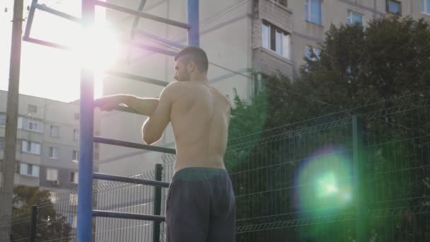 Atleta muscular fazendo ombro e braço alongando-se no corrimão de metal aquecendo antes do treino intenso. Jovem desportista a preparar-se para o treino em terreno desportivo. Conceito de estilo de vida saudável e ativo — Vídeo de Stock