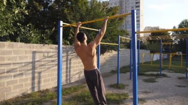 Güçlü sporcu açık havada jimnastik hareketleri sergiliyor. Genç kaslı atlet spor sahasında statik egzersizler yapıyor. Spor yaşam tarzı konsepti. Dolly vurdu.