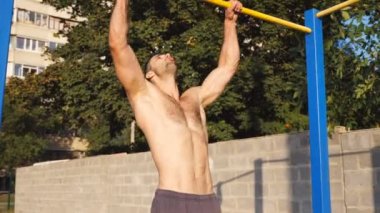 Genç kas sporcusuna yakın yatay bar açıklarında jimnastik numaraları gösteriyor. Spor sahasında spor yaparken statik egzersiz yapan güçlü bir sporcu. Spor yaşam tarzı konsepti