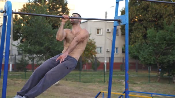 Uomo sportivo che fa una mano tirare su al campo sportivo. Giovane allenamento sportivo su barra orizzontale esterna. Atleta muscolare che esegue esercizi di forza durante l'allenamento. Concetto di stile di vita sano — Video Stock