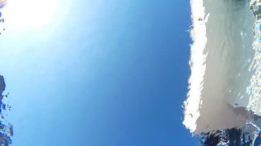 Havuzun dibinden kristal berrak suya atlayan genç adama bakın. Güneşli bir günde havuzda ferahlatıcı bir adam. Erkek turist yaz tatilinde aktif olarak dinleniyor. Yavaş çekim. Yakın çekim.