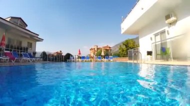 Havuza atlayan genç adam. Adam havuza dalıyor ve suyun altında yüzüyor. Sıcak bir günde erkek turist ferahlatıcı. Yaz tatili kavramı. Yavaş çekim ön görünümü