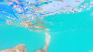 Denizde yüzen erkek ayaklarını kapat. Bacaklarını hareket ettiren ve yüzen tanınmayan bir adam. Erkek turist güneşli bir günde okyanusta ferahlatıcı. Yaz tatili kavramı. POV Yavaş çekim