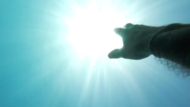 Mão masculina que se estende de debaixo de água para raios solares brilhantes. Braço pedindo ajuda e tentando alcançar o sol. Ponto de vista do homem se afogando no mar ou no oceano e flutuando à superfície. POV em câmara lenta — Vídeo de Stock